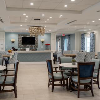 A modern and spacious dining area with elegant chandeliers and multiple tables arranged for seating.