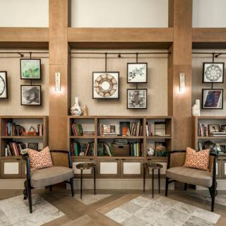 A cozy library nook with bookshelves, chairs, and decorative artwork.