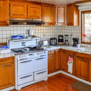 A cozy kitchen with wooden cabinets and a retro stove, filled with various appliances.