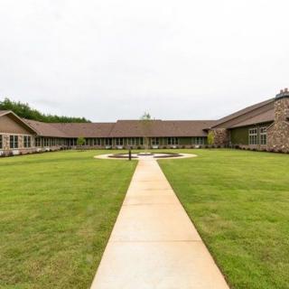 A view of a building with a courtyard, featuring a grassy lawn and a central pathway.