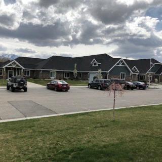 A suburban building with a parking lot and several cars under a cloudy sky.