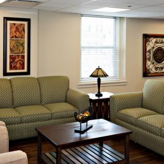 A cozy living room with green sofas, a wooden coffee table, and decorative artwork on the walls.