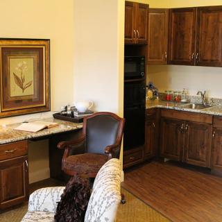 A cozy kitchen area with wooden cabinets and a small desk workspace.