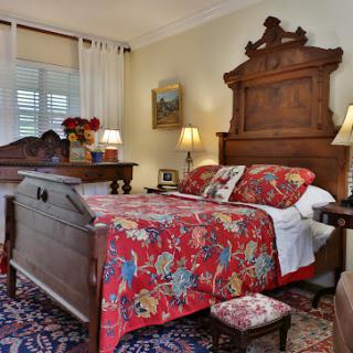A cozy vintage bedroom featuring a beautifully crafted wooden bed and floral bedding.