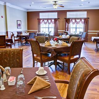 A neatly arranged dining room with well-set tables and chairs, ready for guests.
