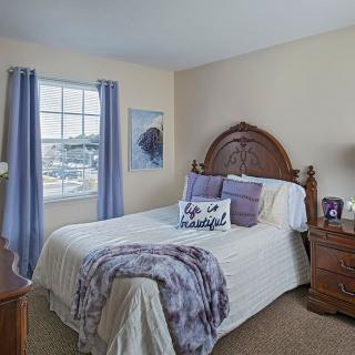 A cozy bedroom with a bed adorned with purple accents and matching curtains.