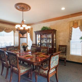 Elegant dining room with a large wooden table, upholstered chairs, and a chandelier.