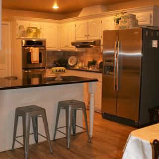 A modern kitchen with stainless steel appliances and counter stools.