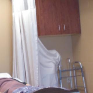 A view of a hospital room featuring a curtain, cabinet, and a walker.
