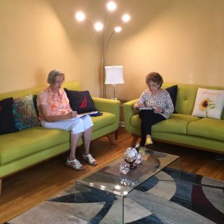 Two people sitting on a green sofa in a cozy living room reading.