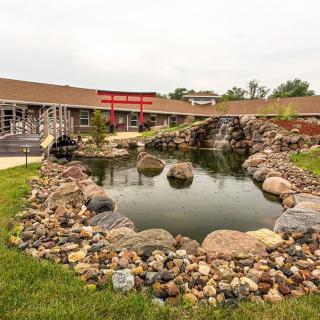 A landscaped area featuring a pond surrounded by rocks, adjacent to a building.