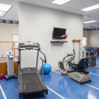 A fitness center with various exercise equipment including a treadmill, a stationary bike, and an exercise ball.