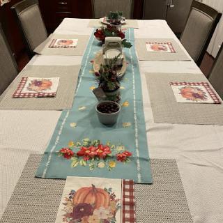 A beautifully arranged dining table featuring an autumn-themed decor with a teapot and decorative place mats.