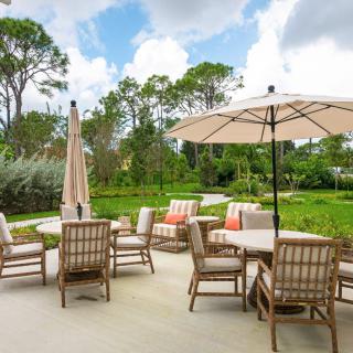 A scenic outdoor patio with comfortable chairs and umbrellas overlooking lush greenery.