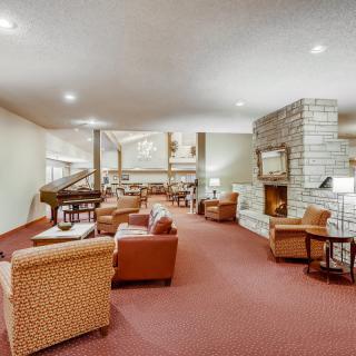 A spacious lounge area with comfortable seating, a fireplace, and a grand piano.