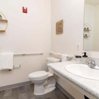 A clean, minimalist bathroom with a sink, toilet, and mirror.