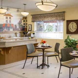 A cozy cafe with tables and chairs, a counter area, and decorative elements including a large clock on the wall.