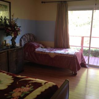 A cozy bedroom with a single bed and large window overlooking a deck.