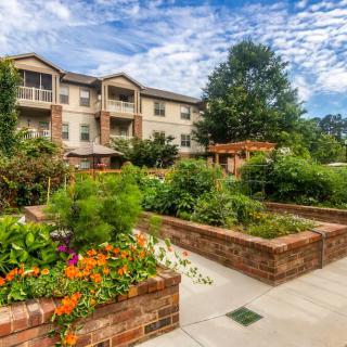 A well-maintained garden in front of an apartment building under a bright blue sky.