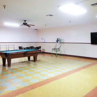 A spacious game room featuring a pool table and a wall-mounted television.