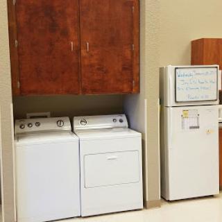 A laundry area featuring a washer and dryer with storage cabinets above, next to a refrigerator.