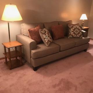 A cozy living room with a sofa, lamps, and decorative cushions.