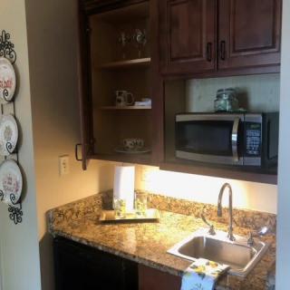 A small kitchen area with wooden cabinets, a granite countertop, a sink, and a microwave.