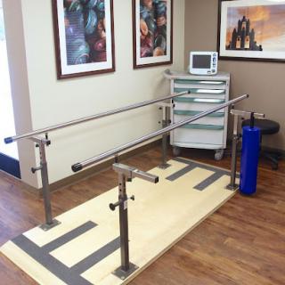 A physical therapy room featuring parallel bars for rehabilitation exercises.