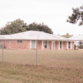 A brick house with a fenced yard in a suburban area.
