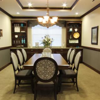 An elegantly designed dining room with a central table and six upholstered chairs, complemented by ambient lighting and tasteful decorations.