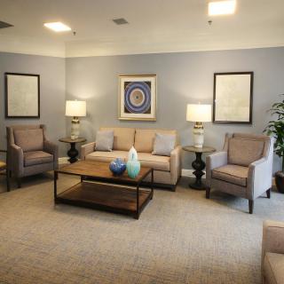 A cozy living room with a sofa, armchairs, and a coffee table, complemented by soft lighting and tasteful artwork.