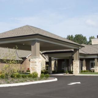 A modern building entrance with a covered driveway and landscaped surroundings.