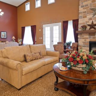 A cozy living room with a beige sofa, a wooden coffee table with floral decor, and a stone fireplace.