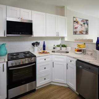 A modern kitchen with white cabinets and stainless steel appliances.