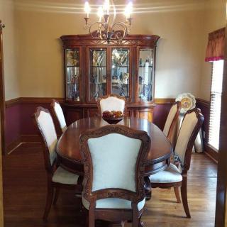 An elegant dining room with a wooden table and chairs, complemented by a china cabinet and chandelier.