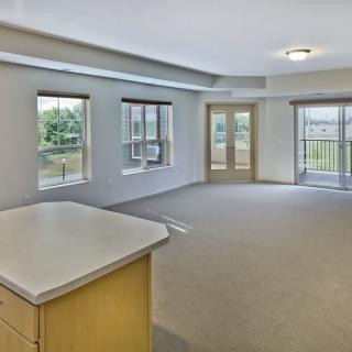 An empty apartment living room featuring large windows and ample natural light.