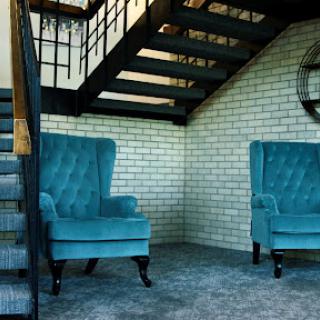 A cozy nook featuring stylish teal armchairs under a modern staircase.