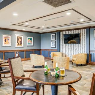 A comfortable lounge area with tables, chairs, and artwork on the walls.