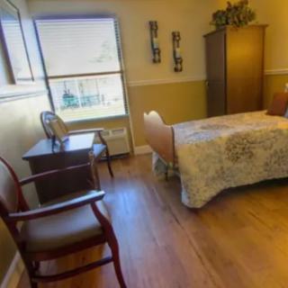 A cozy bedroom with a bed, chair, and wardrobe by the window.