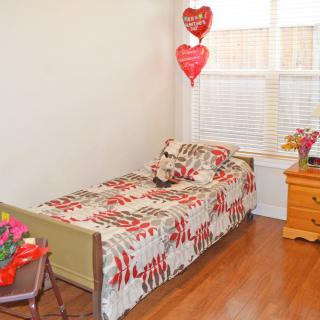 A cozy bedroom with a single bed, featuring floral bedding and heart-shaped decorations.