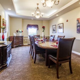 A well-decorated dining room with a large table surrounded by chairs, illuminated by a chandelier.