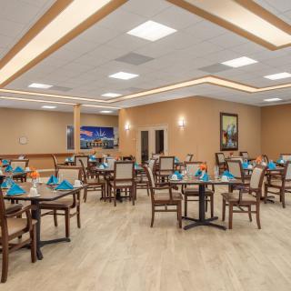 An elegant dining room setup with multiple tables and chairs arranged neatly under warm lighting.