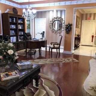 A well-decorated living room featuring a home office setup with a desk and bookshelf.