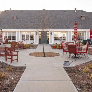 A cozy patio with outdoor seating and red umbrellas in front of a residential-style building.