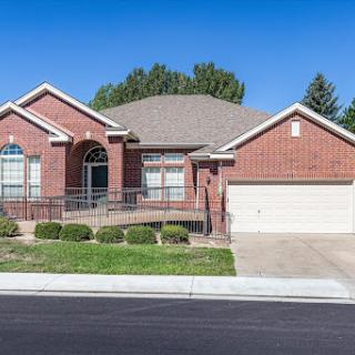 A charming single-story brick house with a well-maintained front yard and attached garage.