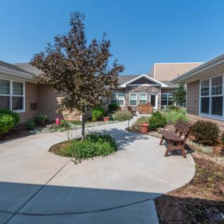 A peaceful courtyard with a central tree, surrounded by benches and landscaped gardens.