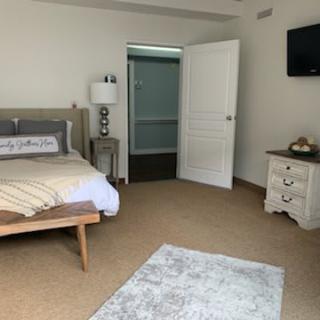 Modern bedroom with a bed, nightstand, lamp, and open door.