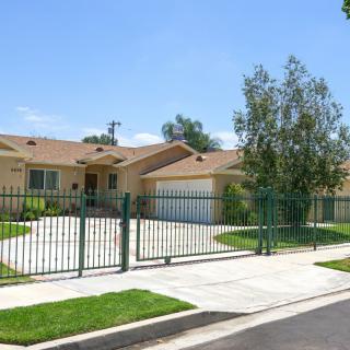 A suburban house with a fenced yard and a driveway.