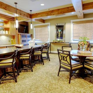 A cozy kitchen and dining area with wooden beams, elegant chairs, and warm lighting.