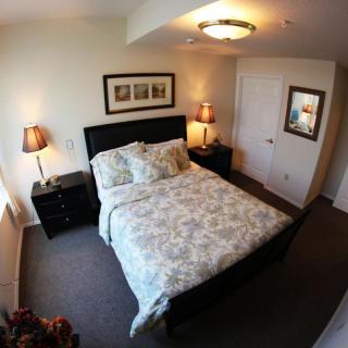 A cozy bedroom with a neatly made bed, flanked by two nightstands and lamps, featuring a mirror on the wall.